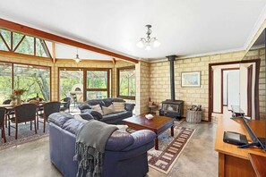 Un salón espacioso con chimenea, ventanas amplias y una zona de estar acogedora.