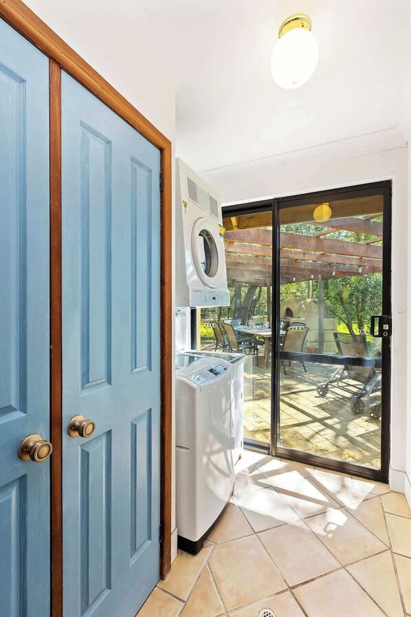 A room with a blue door, a washing machine, and a patio with outdoor furniture.