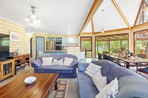 Un amplio espacio de sala con sofá, mesa de centro y cocina al fondo.