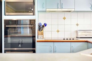 Una cocina con electrodomésticos de acero inoxidable, armarios azul claro y salpicadero de azulejos.