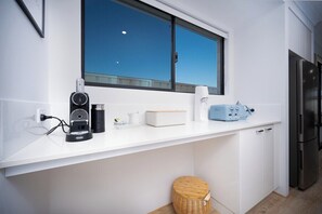 A modern kitchen with a white countertop, a coffee maker, a toaster, and a refrigerator. - ShoreAcres Retreat—Peaceful Beach Hideaway (Dunsborough)