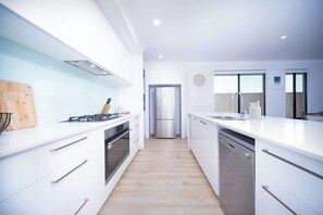 A modern kitchen with white cabinetry, stainless steel appliances, and a wooden countertop.