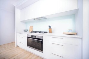 A modern kitchen with white cabinetry, a built-in oven, and a gas stove.