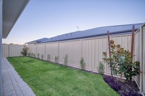A fenced backyard with a well-maintained lawn and small shrubs. - ShoreAcres Retreat—Peaceful Beach Hideaway (Dunsborough)