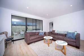 A modern living room with two sofas, a small coffee table, and a glass door leading to a balcony.