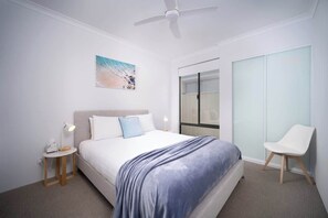 A modern hotel room with a bed, a nightstand, a chair, a ceiling fan, and a painting on the wall. - Shoreacres Retreat - Your next holiday in paradise (Dunsborough)