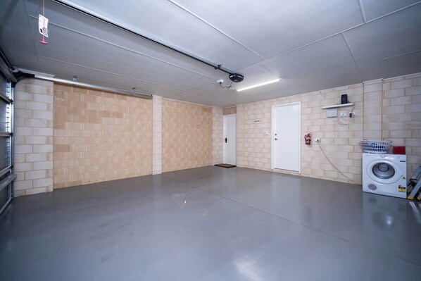 A clean, empty room with a washing machine, a door, and a light fixture.