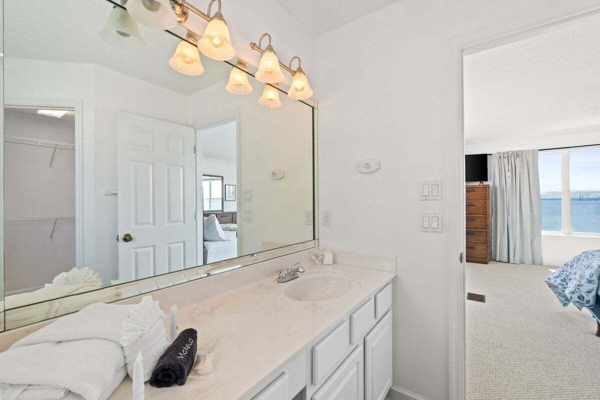 A bathroom with a large mirror, two sinks, and a vanity with drawers.