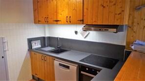 A kitchen with wooden cabinets, a black countertop, a dishwasher, and a stove.
