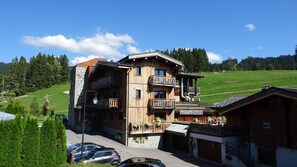 A multi-story wooden building with balconies, a sign reading 'CYCHA', and a view of a green landscape.