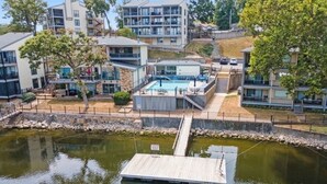 A residential building with a swimming pool, a dock, and a small water body. - Feel right at home in this family-sized new listing at the 1MM on the Lake!   (Lake Ozark)