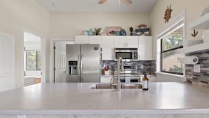 A modern kitchen with stainless steel appliances, a large island, and a view of the outdoors. - Feel right at home in this family-sized new listing at the 1MM on the Lake!   (Lake Ozark)