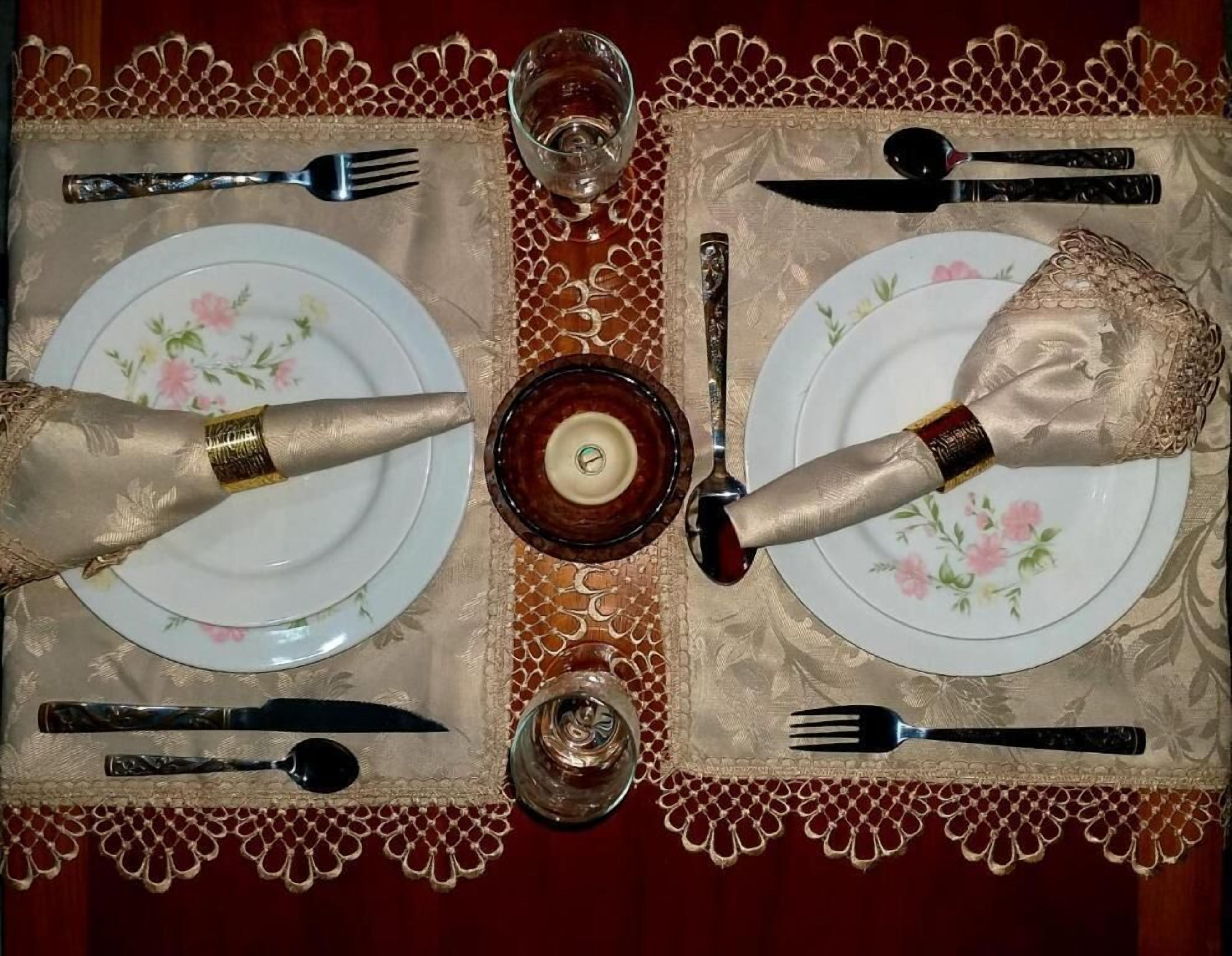 A table set with fine china, silverware, and a glass of red wine.