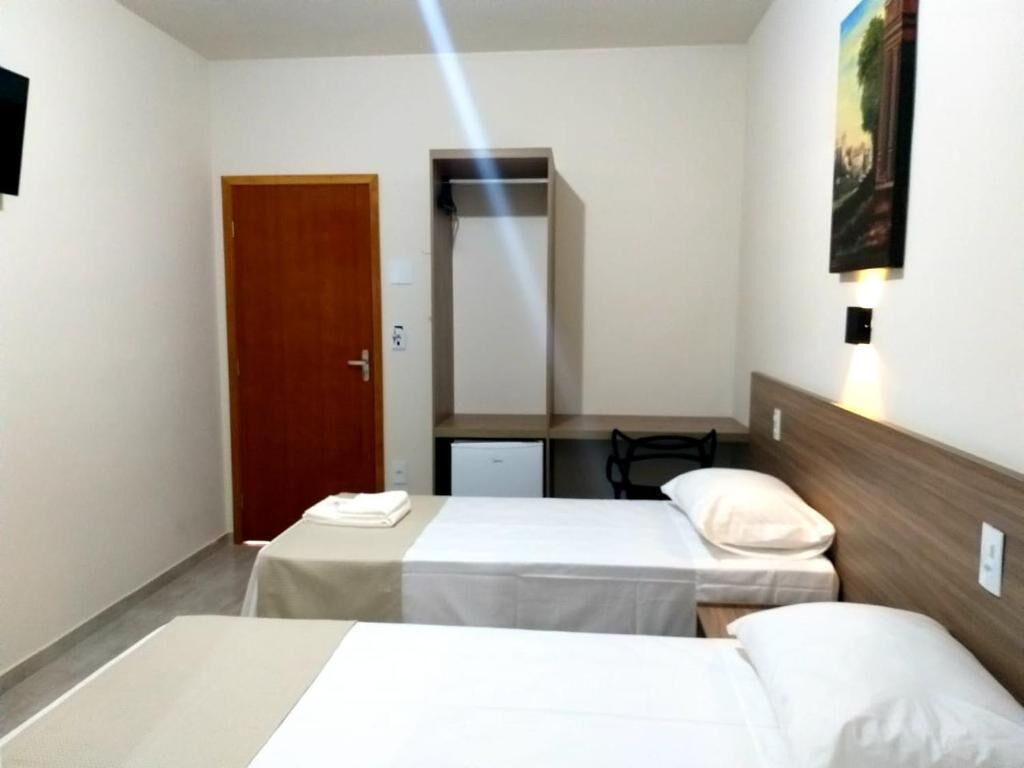 A hotel room with two single beds, a desk, a chair, and a wardrobe.