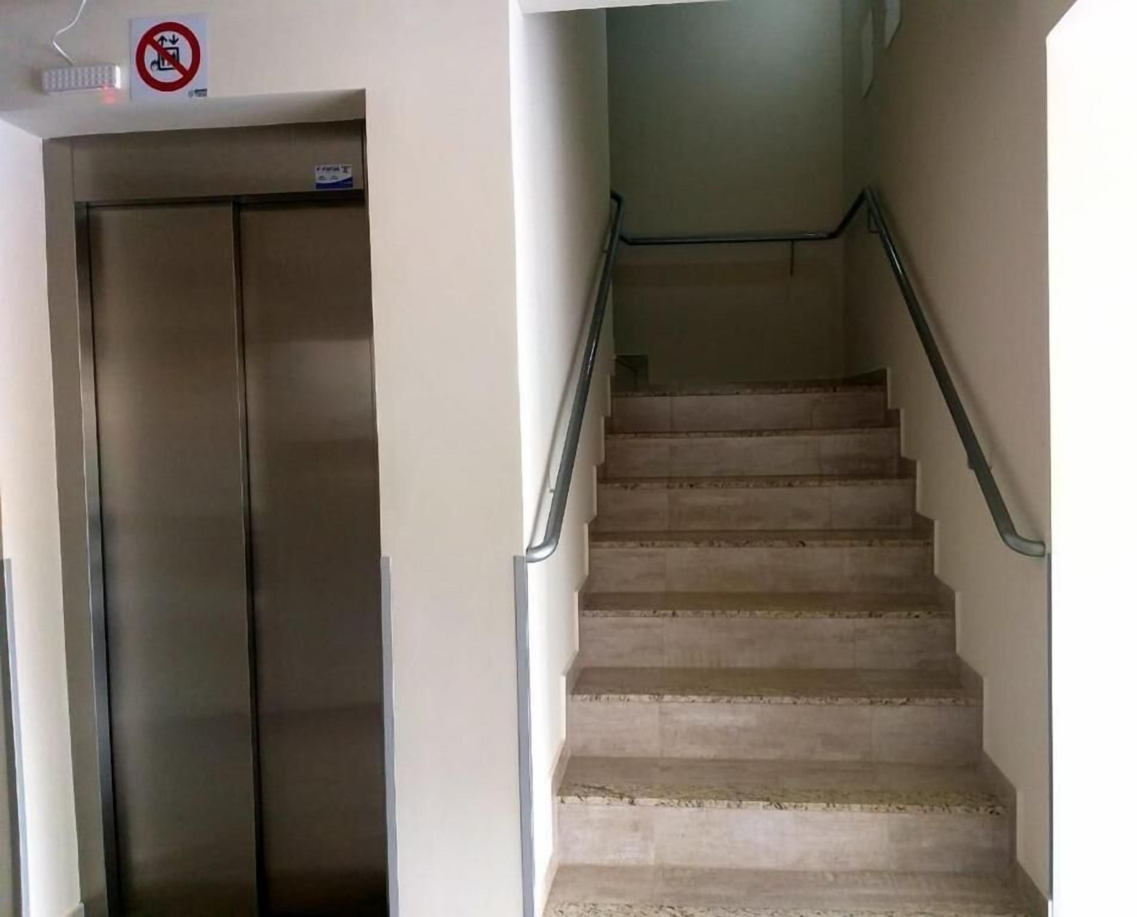 Una escalera con barandillas metálicas y la puerta cerrada de un ascensor.