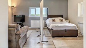 Ett modernt sovrum med en säng, ett sängbord och en tv.