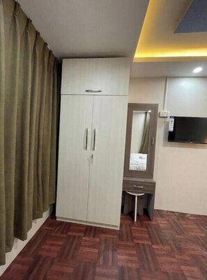 Comfortable room with a wardrobe, vanity, and TV.