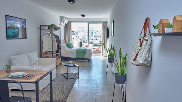 Een modern appartement met een balkon, een eethoek en een zithoek.