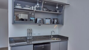 Een moderne keuken met een inbouwvaatwasser, een roestvrijstalen spoelbak en een aanrecht met waterkoker en rijstkoker.