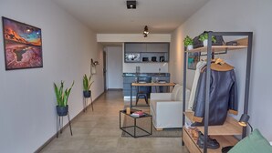 Een moderne hotelkamer met een bed, een bureau, een stoel, een kledingkast en een keuken in de achtergrond.