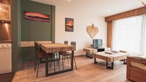 Uma sala de estar moderna com uma mesa de jantar de madeira, um sofá e uma televisão.