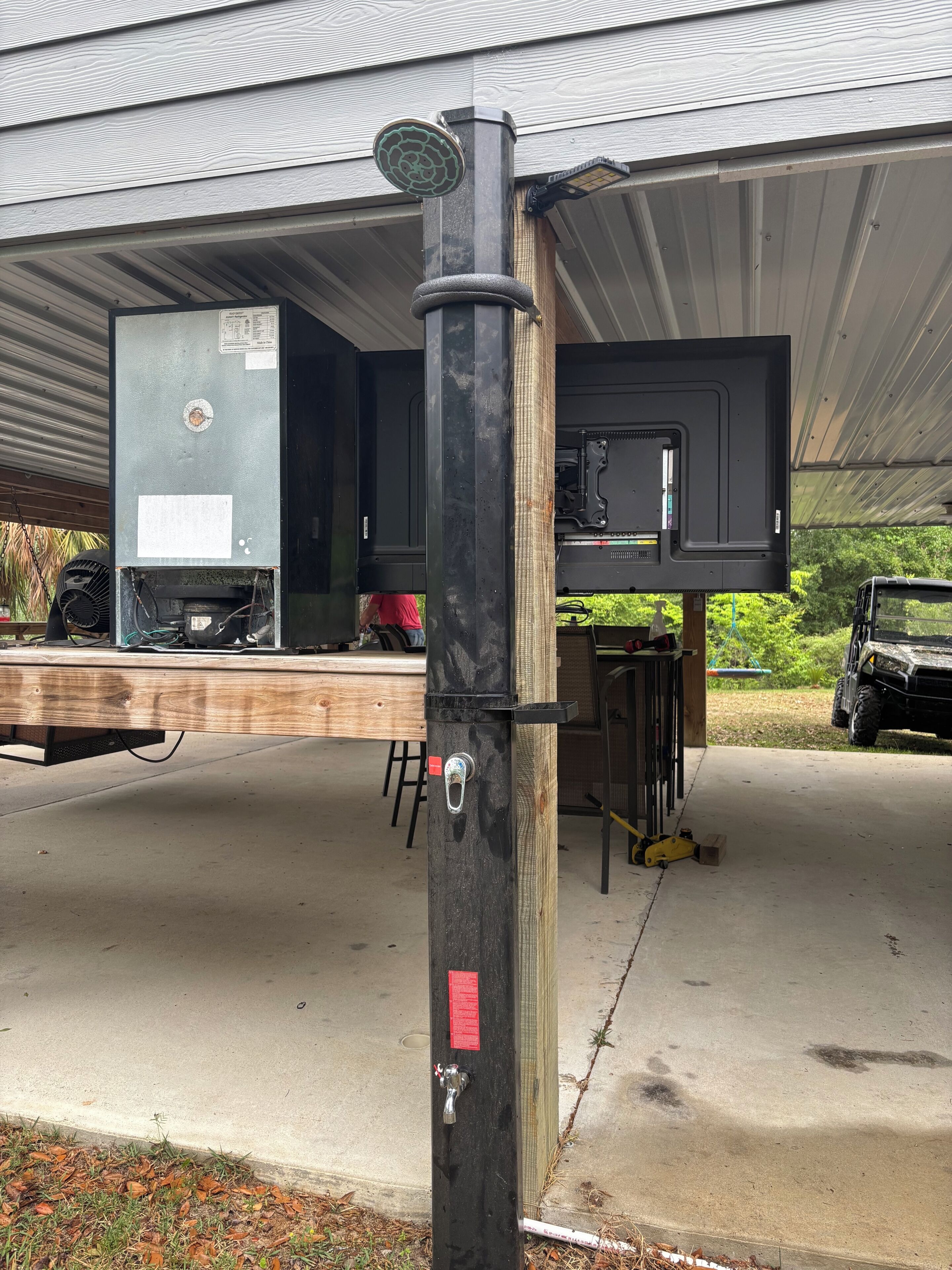 A garage with a black utility pole, a metal garage door, and a vehicle parked inside.