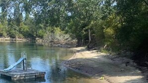 A sandy beach with a small dock and a green kayak. - Charming waterfront barndominium on the beautiful spring-fed Chipola River. (Altha)