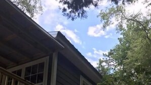 A two-story house with a balcony and a covered porch area. - Charming waterfront barndominium on the beautiful spring-fed Chipola River. (Altha)