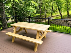 Una mesa de picnic de madera en un balcón con barandilla de metal negro.