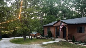 Una casa con camino de grava, un porche de madera y una bandera estadounidense.