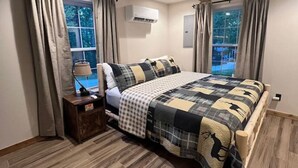 A bedroom with a bed, a ceiling fan, an air conditioning unit, and a window with curtains. - 4 Bedroom Cabin Retreat (Imperial)