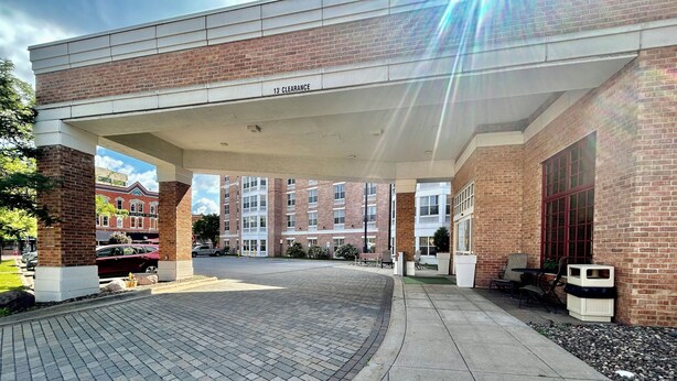 A covered outdoor area with a brick building, a paved walkway, and a clear sky. - Pearl Street Hotel & Suites (La Crosse)