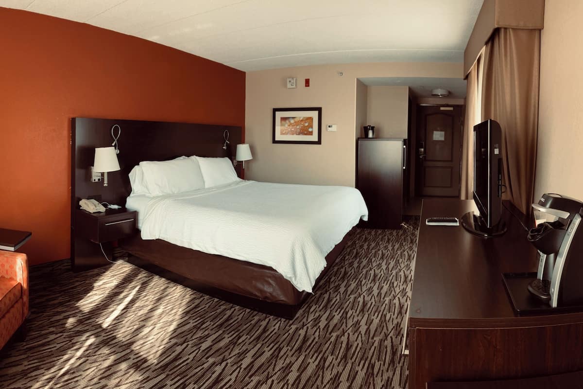 Ein Hotelzimmer mit Bett, Schreibtisch, Stuhl, Fernseher und Kühlschrank.
