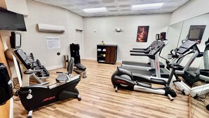 A fitness center with cardio machines, weight machines, and a mirrored wall. - Pearl Street Hotel & Suites (La Crosse)