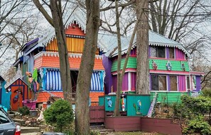Une maison aux couleurs vives et au style fantaisiste, dotée de plusieurs niveaux et d’une décoration extérieure éclatante.