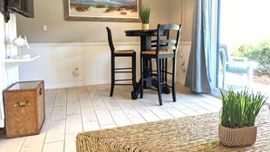 Un coin repas avec une table et des chaises, un tableau au mur, un luminaire suspendu et une vue par la fenêtre.
