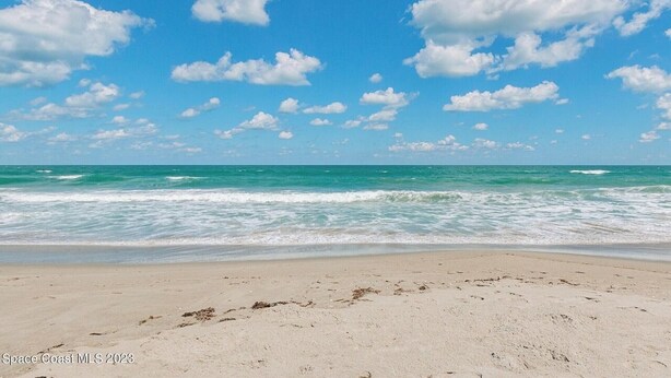 Une plage avec un ciel dégagé et des vagues sur l’océan.