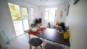 A modern kitchen with a dining table, two chairs, a TV, and a plant. - Félix T2 accès plage à Ste Luce

 (Sainte-Luce)