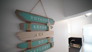 A wall-mounted sign with the words "VOYAGE," "RÊVER," "ET," and "EXPLORER" in a rustic style. - Félix T2 accès plage à Ste Luce

 (Sainte-Luce)
