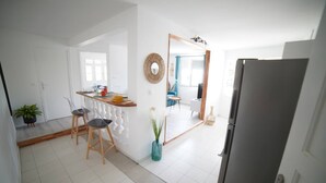 Una cocina moderna con comedor, paredes blancas y un espejo grande.