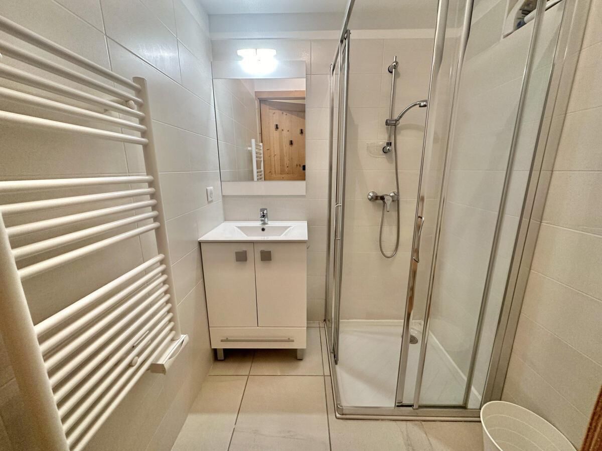 A bathroom with a glass shower enclosure, a white sink vanity, and a towel rack.