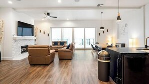 Amplia sala de estar con chimenea, un gran conjunto de sofás, comedor y cocina con encimera de mármol.