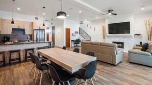 A modern kitchen with a wooden dining table and chairs, a built-in oven, and pendant lighting. - Beachfront Surfside Beach House w Ocean Views & Game Room - 5BR - Sleeps 16 (Freeport)