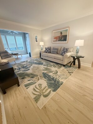 A living room with a sofa, a coffee table, a rug, and a painting on the wall.