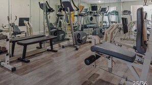 Un gimnasio con diversos equipos de ejercicio, entre ellos cintas de correr, bicicletas estáticas y máquinas de pesas.