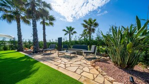 Un espace patio doté d’un sol en pierre, de mobilier d’extérieur et de palmiers.