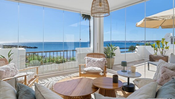 Un balcón amplio con vistas al mar, amueblado con un sofá, sillas y una mesa.