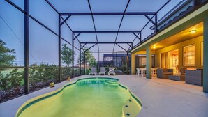 Une piscine avec un patio couvert, des chaises longues et un espace extérieur bien éclairé, aménagé pour se détendre.