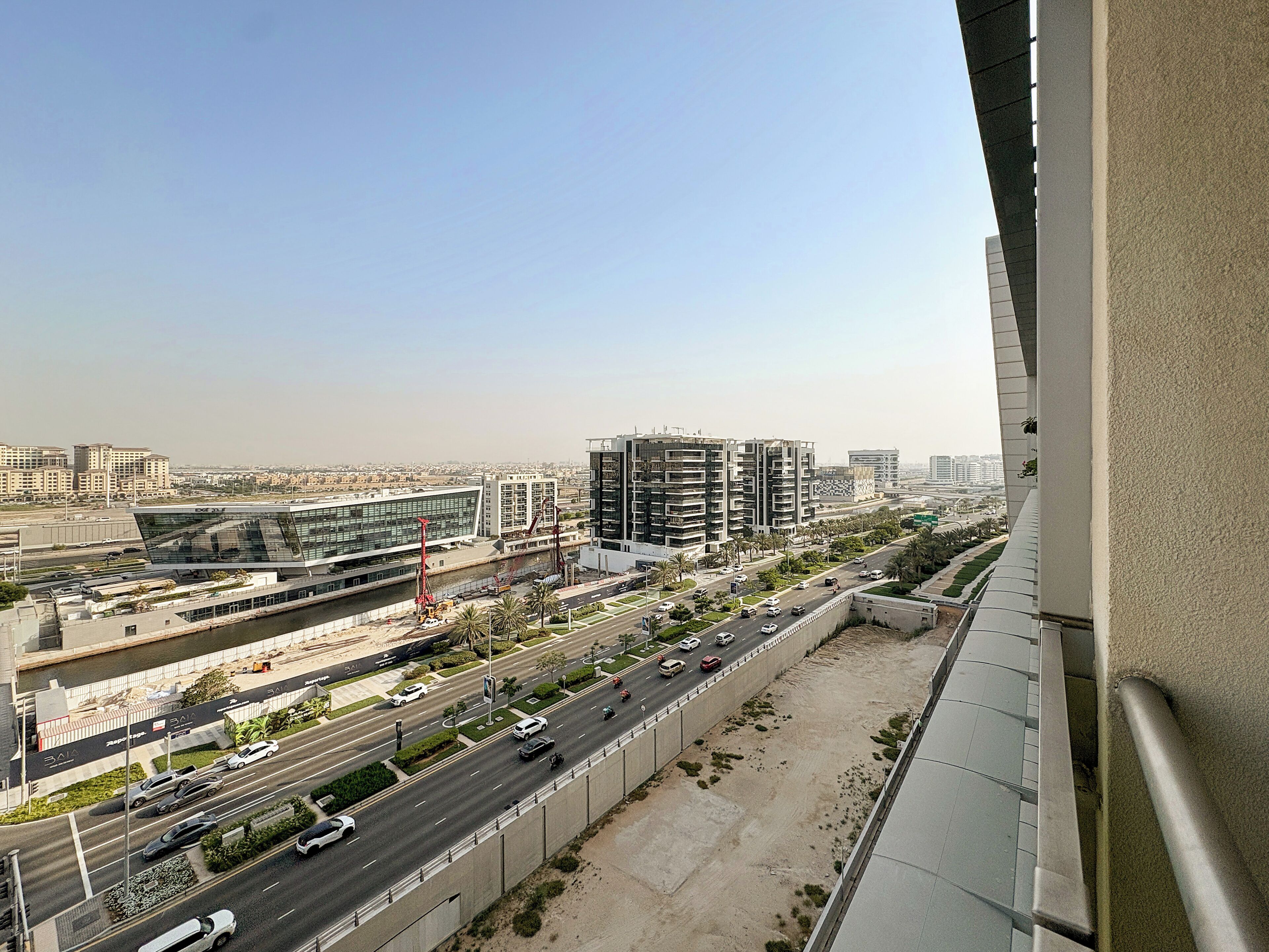 A cityscape with modern buildings, a river, and a busy road.