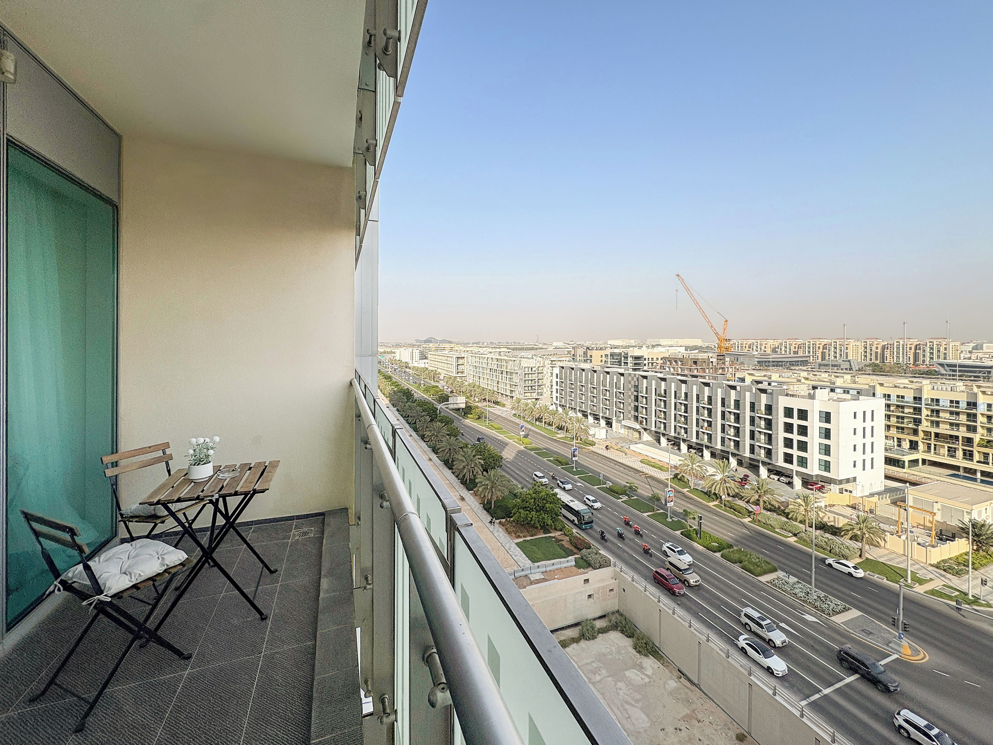 Een balkon met uitzicht op een stadsbeeld, inclusief een weg met voertuigen en een bouwplaats.